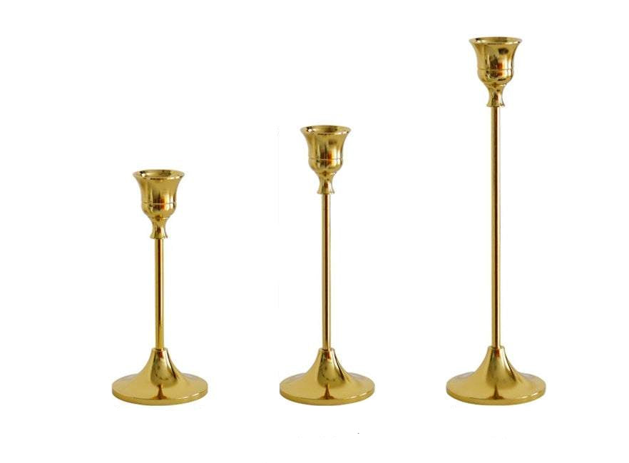 Vintage golden candle holder set with varying heights and elegant design.