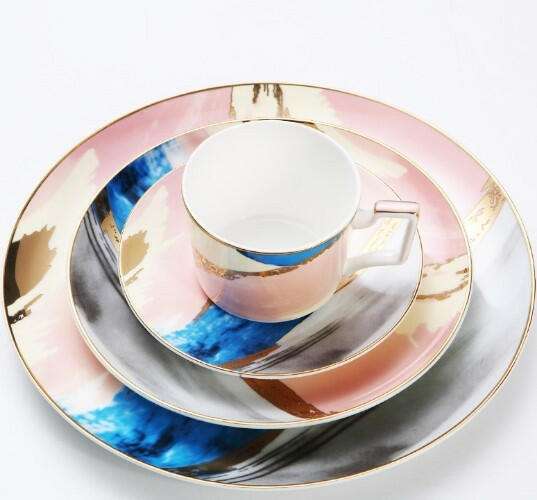 Colorful porcelain hand-painted dishes set with vibrant blue, pink, and gold abstract designs.