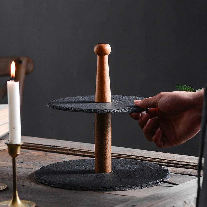 Rustic multilayer board with wood and black stone tiers for elegant food presentation.