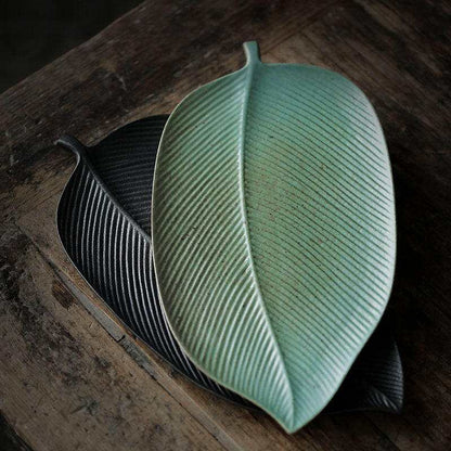 Leaf-shaped vintage ceramic tray with intricate patterns and a soft, aged glaze.