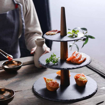 Multilayer board tray with wood and black stone tiers for elegant food presentation.