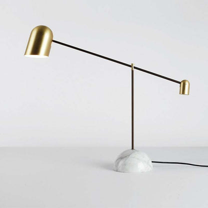 Minimalist marble table lamp with gold dome and modern vertical rod lighting.