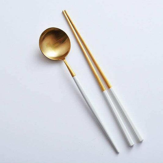 Sushi cutlery set featuring gold-toned spoon and chopsticks with white handles.