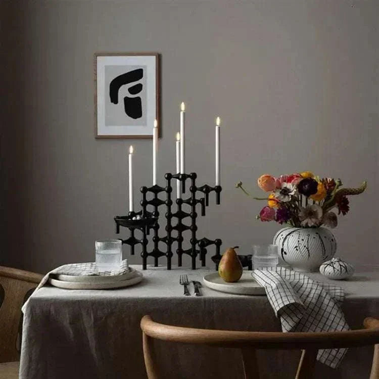 Metal sculptural candle holder with modular design on a dining table setting.