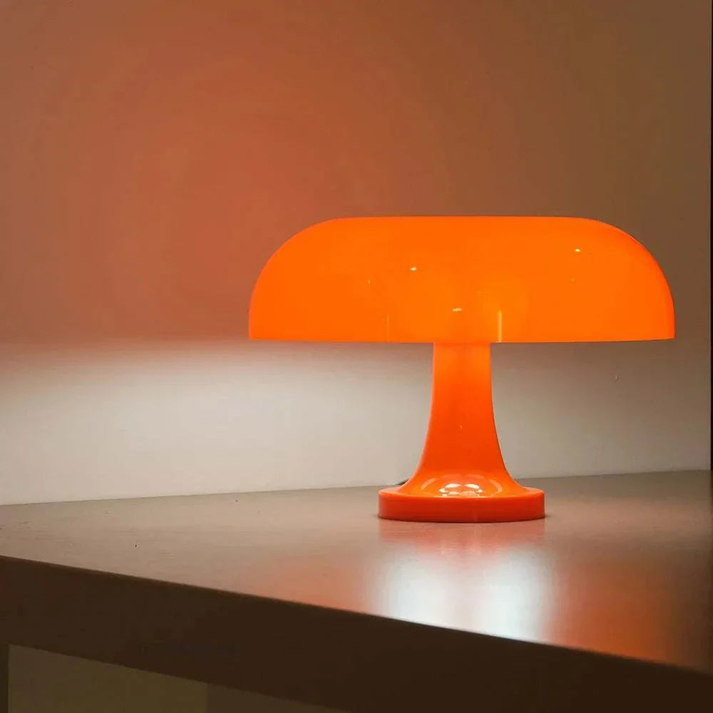 Mushroom table lamp with an orange dome design on a shiny surface, illuminating a stylish modern decor.