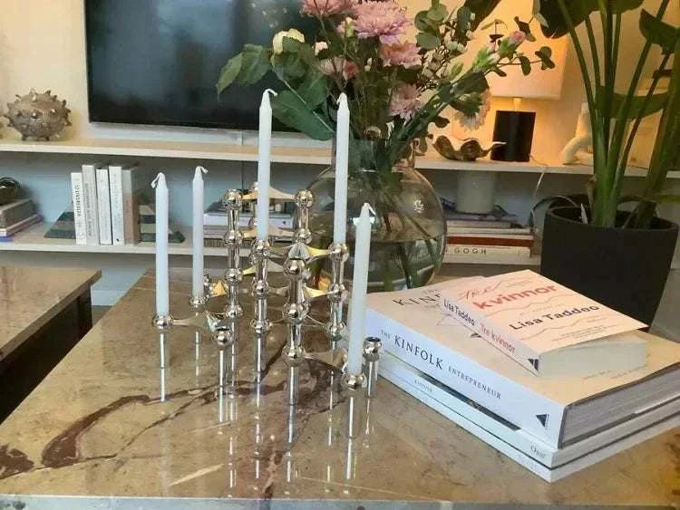 Metal sculptural candle holder with modular arms on a marble surface, enhancing elegant home decor.