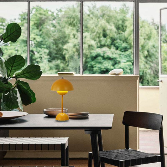 Yellow FlowerPot Lamp on dining table by a window with greenery outside.